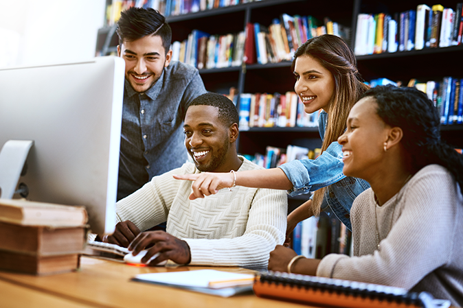 Group of college students working together on library computer