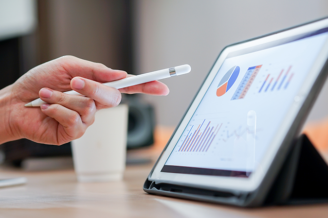 close up salesman employee hand using stylus pen to pointing on tablet screen to show company profit monthly in the meeting event at conference room , business strategy concept
