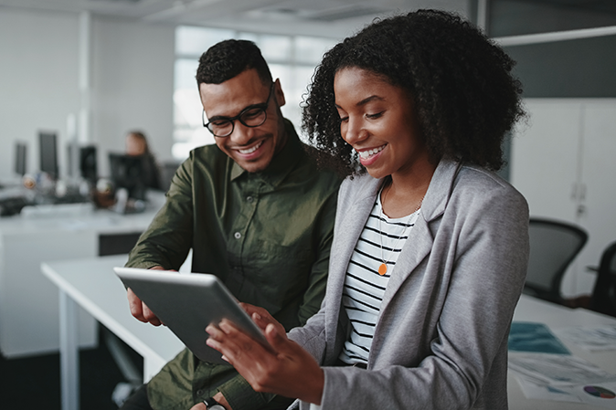 Professional young businesspeople using tablet computer smiling in office
