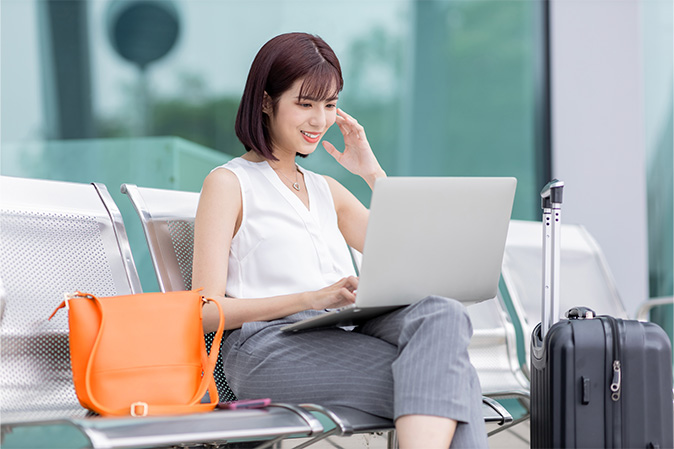 asian young woman sit on a chair outside and use laptop on her business trip