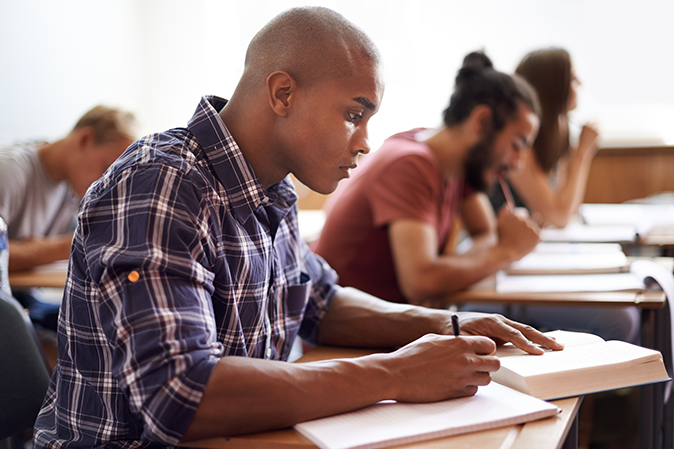 Male student studying in full classroom