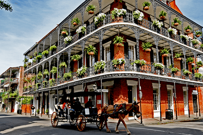 Beautiful curved building on a street in New Orleans with a horse and carriage going by
