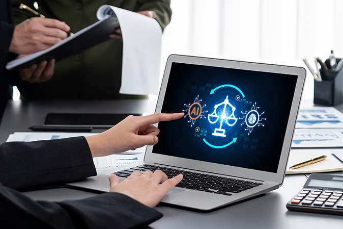 Professional sitting at a desk in an office points to an AI symbol on a laptop