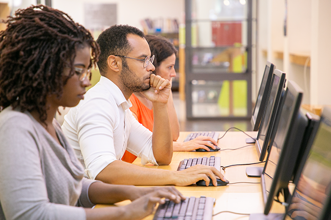 Group of multi-racial students working on computers in class