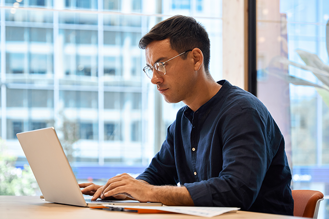 Young man sitting at a desk typing on a laptop
