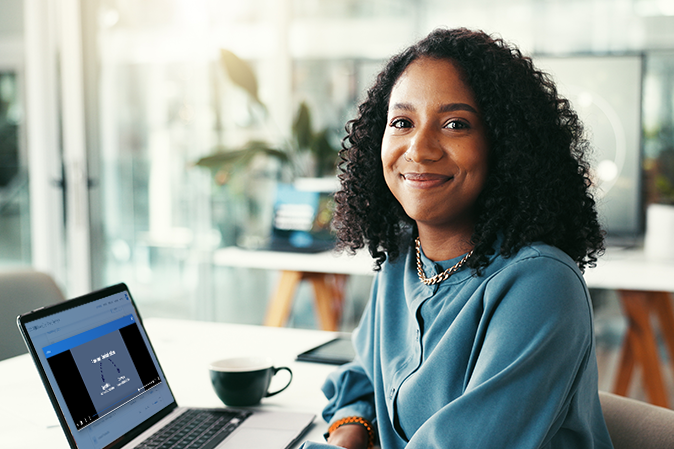 Young woman smiling while sitting at her desk in front of laptop