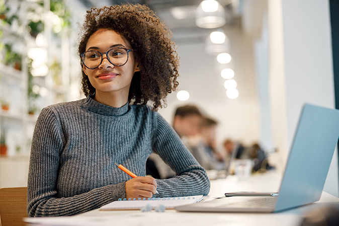 Smiling afro american woman student studying online while sitting in cozy cafe. High quality photo