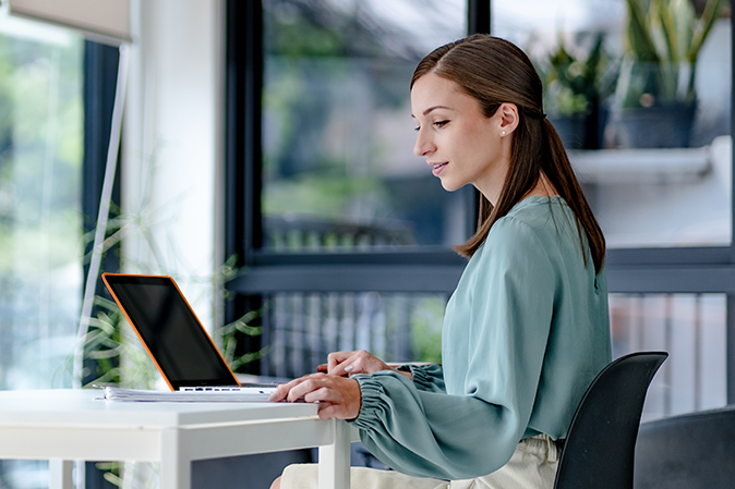 woman sitting in brightly lit office with a laptop