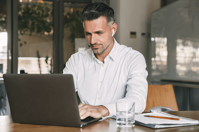 Middle man typing on a laptop sitting at a desk in an office