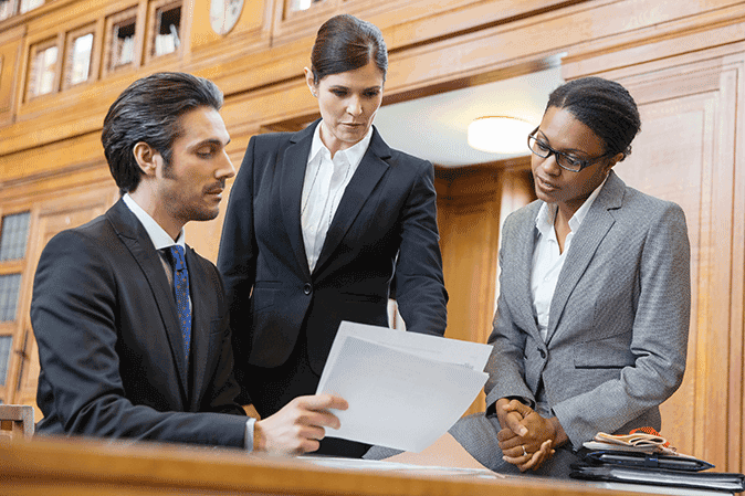 Three young lawyers looking over files in a courtroom