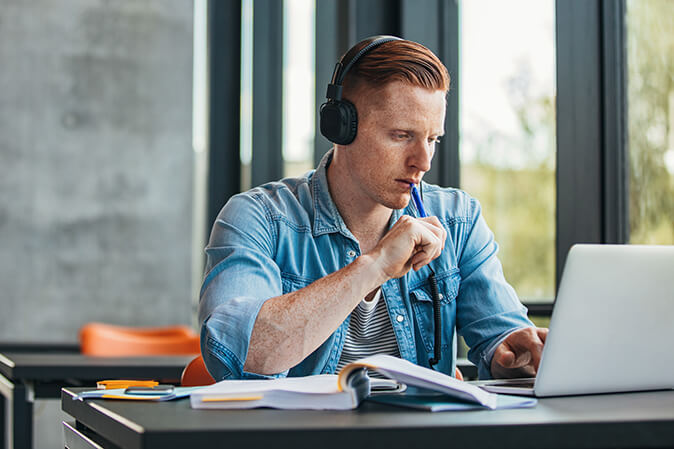 Young man studying on laptop in a classroom