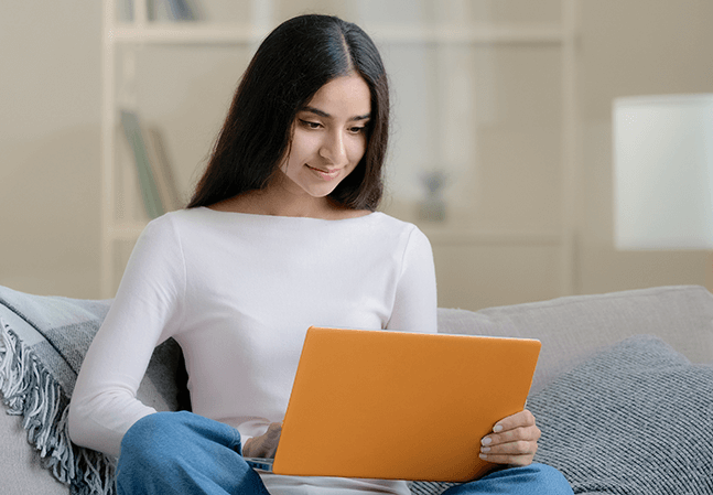 Young woman holding laptop sitting on couch in living room