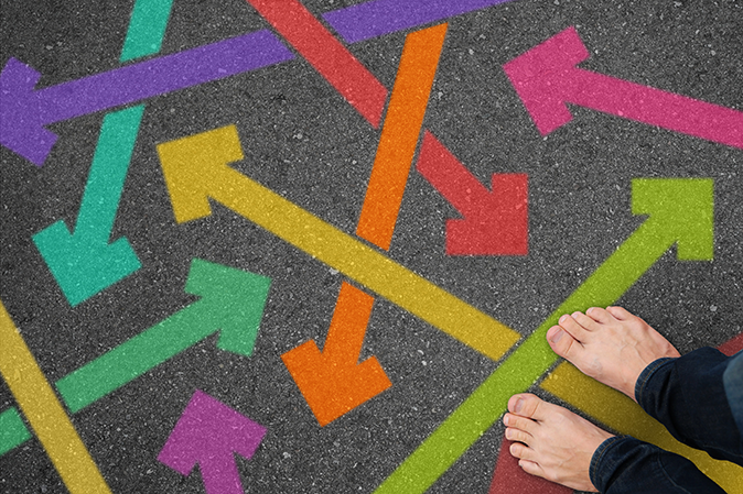 A pair of bare feet on the pavement with a bunch of colored arrows pointing in different directions