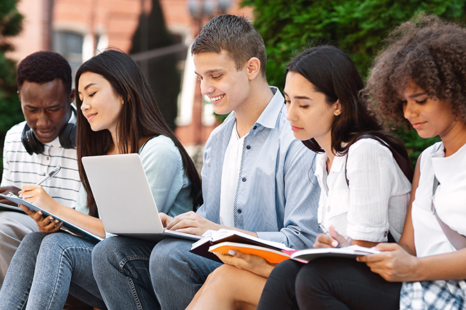Five students outside on campus studying together