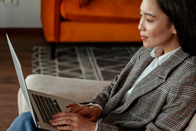 Young woman typing on a laptop sitting on a couch