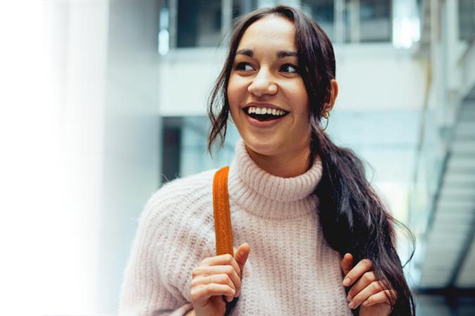 Happy female student going for class. Young woman smiling in college campus.