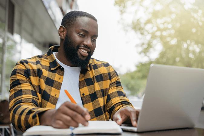 BARBRI student with yellow checked shirt taking notes at laptop