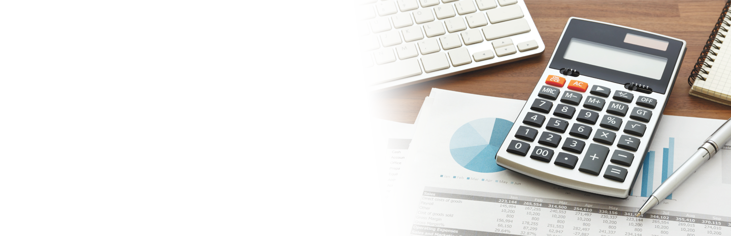Calculator sitting on top of financial documents in front of a laptop on a desk