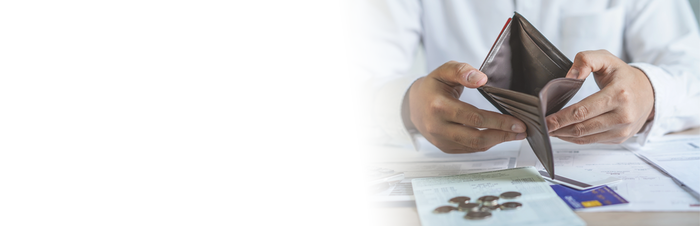 Man holding open an empty wallet with coins and credit cards on the table