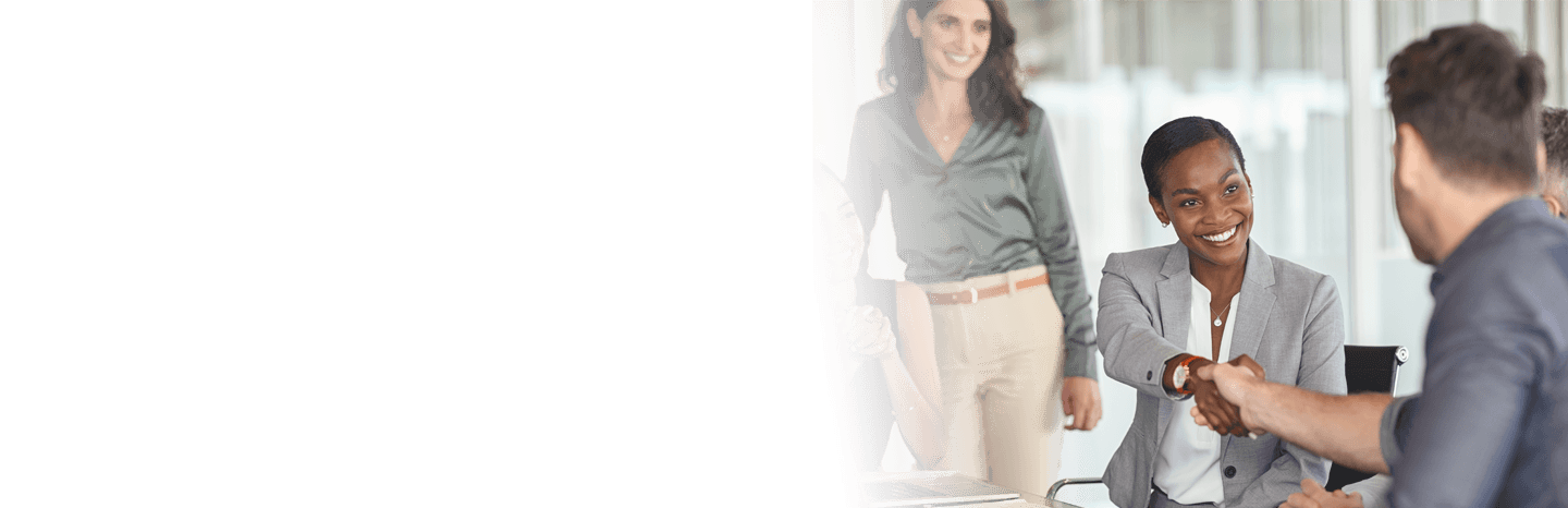 Young professional woman shaking the hands of a man with coworkers observing