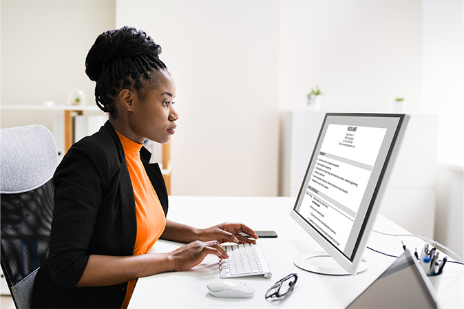 Young woman working on her resume on her laptop