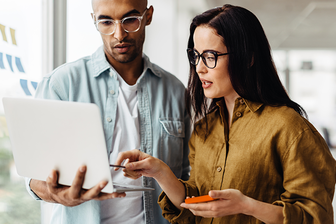 Man holding laptop while woman next to him points at laptop