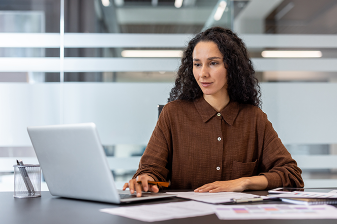 Middle-aged woman in an office typing on a laptop