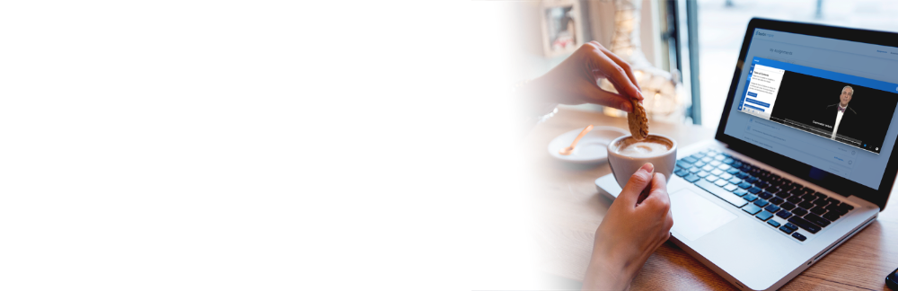 Person dunking a cookie in a coffee while watching a video on a laptop